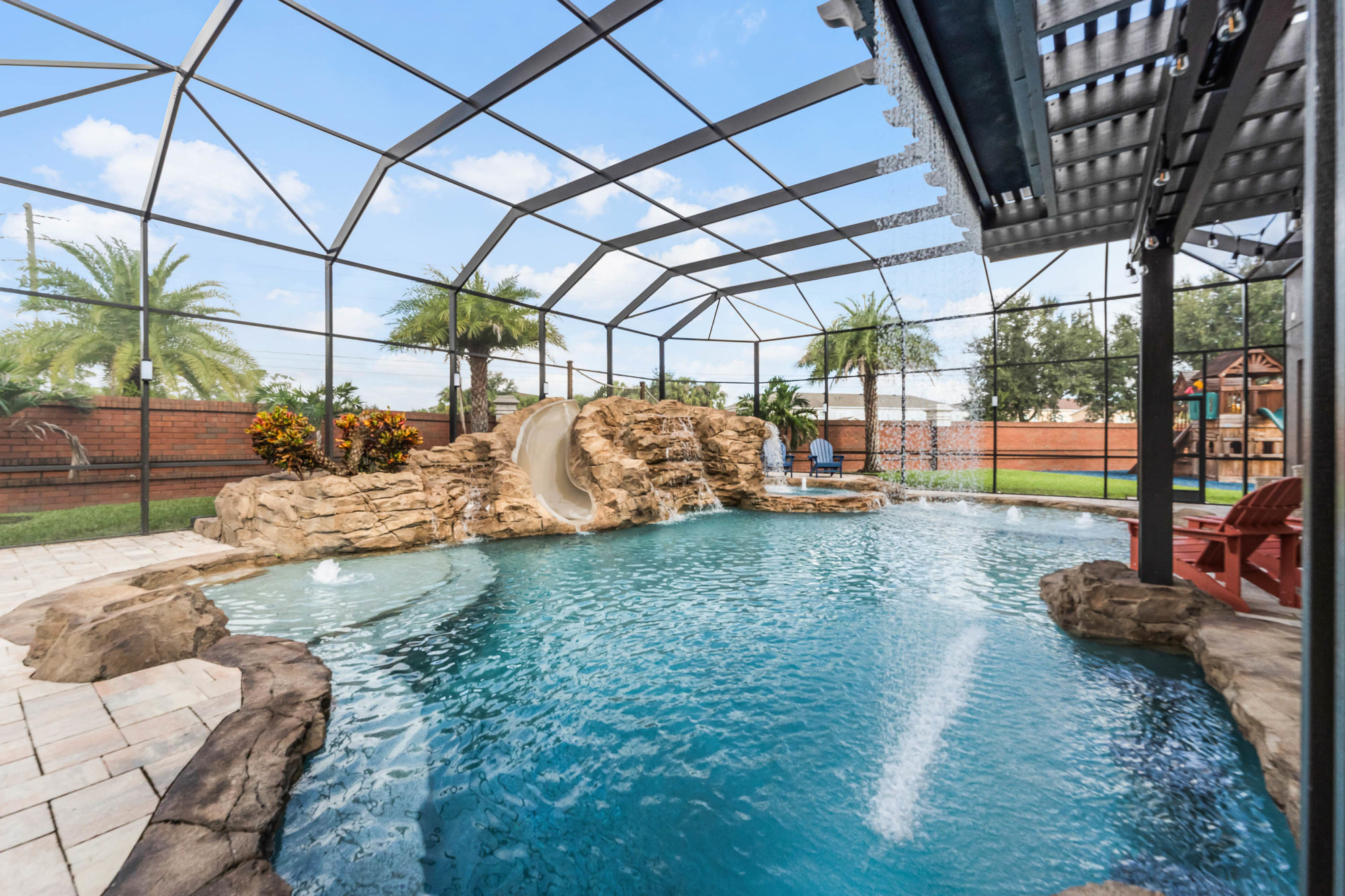 screened in pool with waterfall and slide on rock decor
